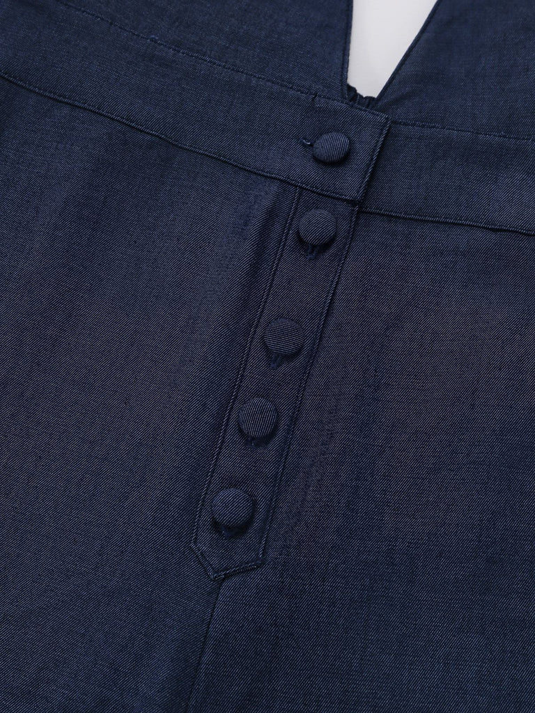 Close-up of the front waistline featuring elegant fabric-covered buttons on the navy jumpsuit.