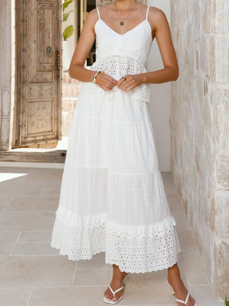 Woman wearing a white dress with intricate detailing in an outdoor setting.