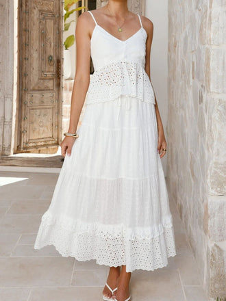Woman wearing a white lace dress standing in front of a stone wall.