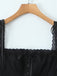 Black lace-trimmed top on a wooden hanger against a white background