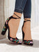 Black high-heeled shoes with floral embroidery worn with rolled-up jeans.