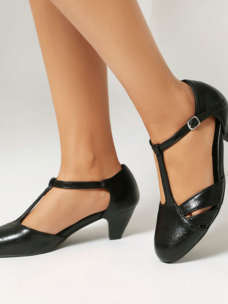 Black high-heeled shoes worn with beige stockings on a light background