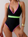 Black swimsuit with neon green and pink trim on a plain background