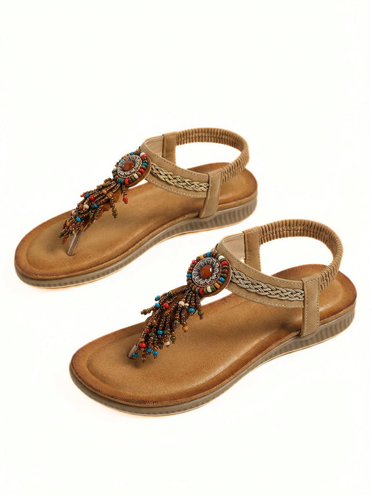 Pair of tan sandals with decorative elements on a white background
