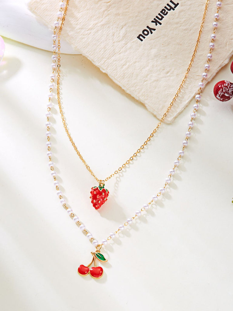 Necklace with strawberry and cherry charms on a white background