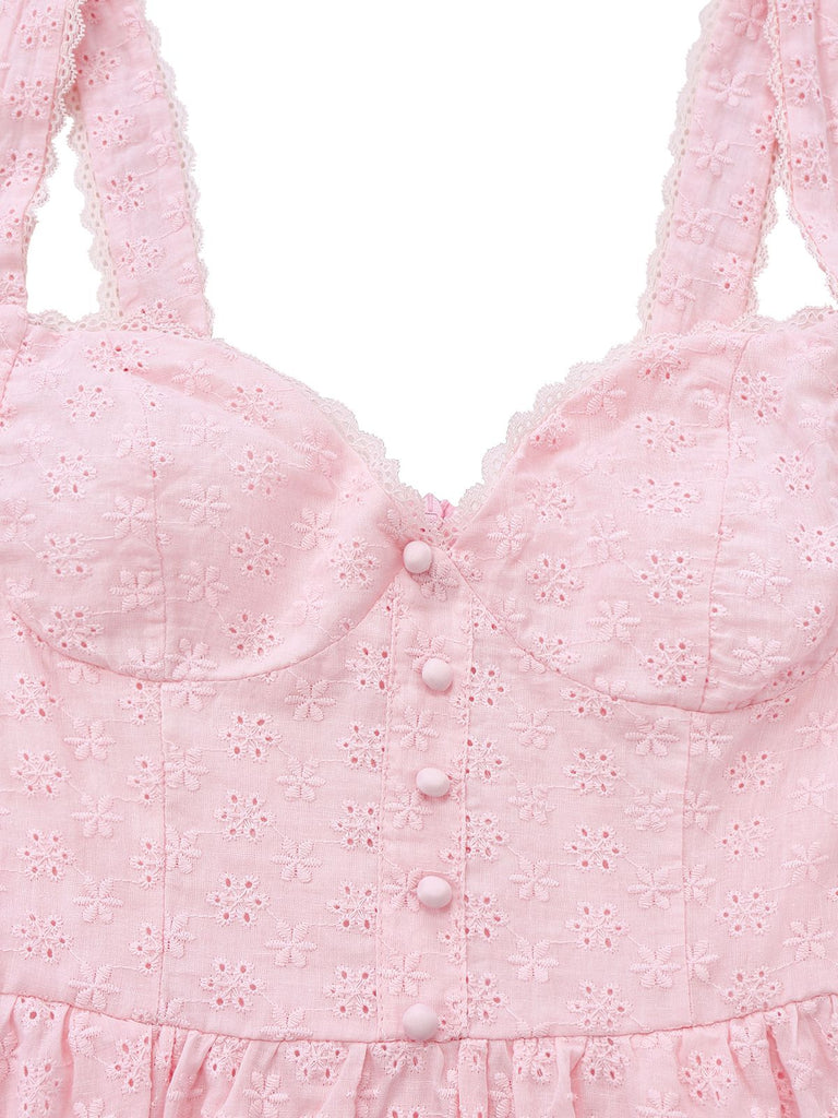 Close-up of a pink dress with floral embroidery and buttons on a white background