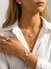 Person wearing a Pink necklace with pink floral pendants, matching ring, and bracelet on a white background.