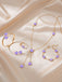 Purple jewelry set with purple stones on a beige fabric background