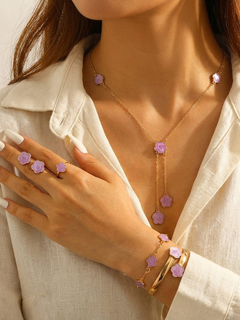 Woman wearing a Purple necklace, bracelet, and earrings with a white top.