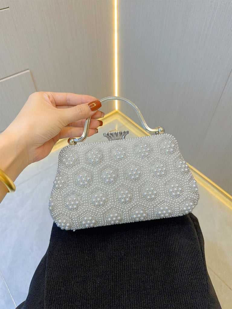 Hand holding a beaded handbag against a neutral background
