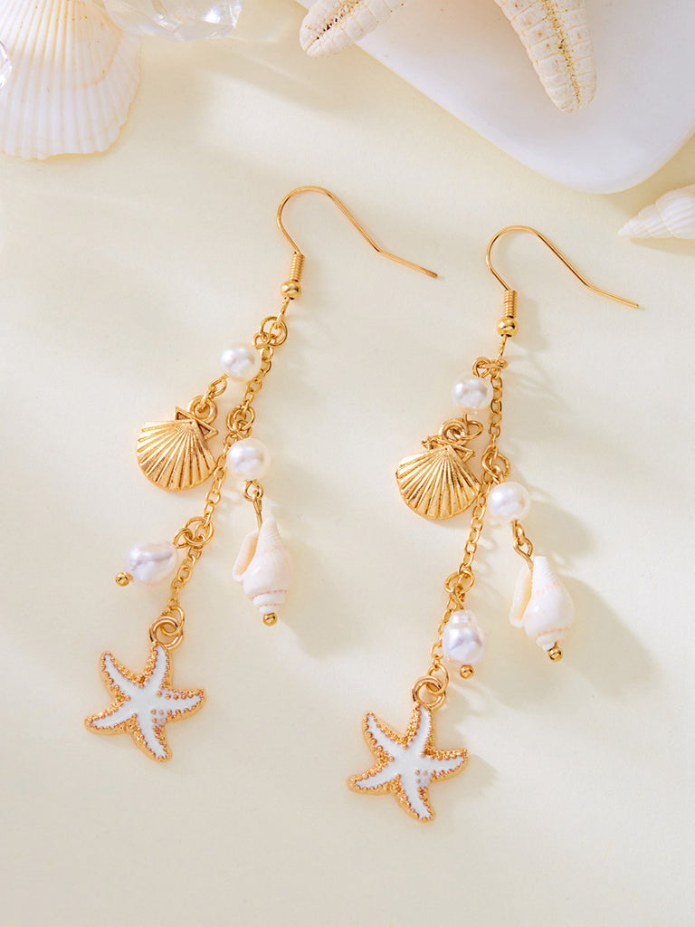 Gold earrings with starfish and shell designs on a beige background