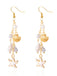 Gold and pearl earrings with starfish and shell designs on a white background