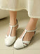 White sandals worn with a light-colored skirt on a neutral floor.