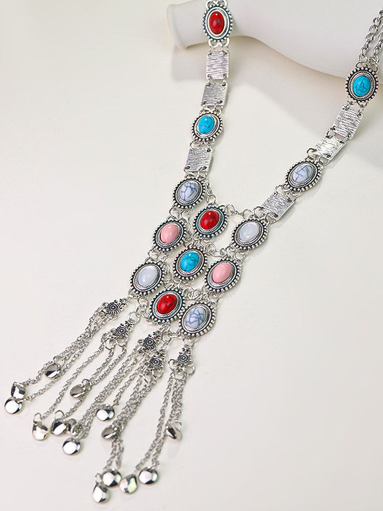 A long silver bohemian statement necklace featuring turquoise, coral, and white stones with a cascading chain fringe.
