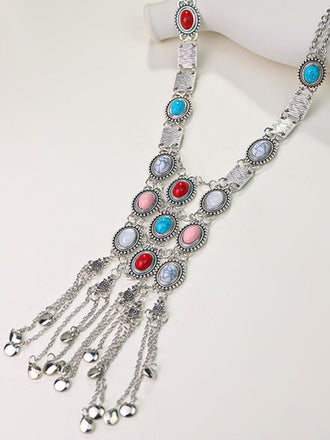 A long silver bohemian statement necklace featuring turquoise, coral, and white stones with a cascading chain fringe.