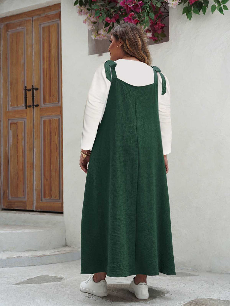 Back view of the forest green pinafore maxi dress highlighting the square neckline and long pleated skirt.