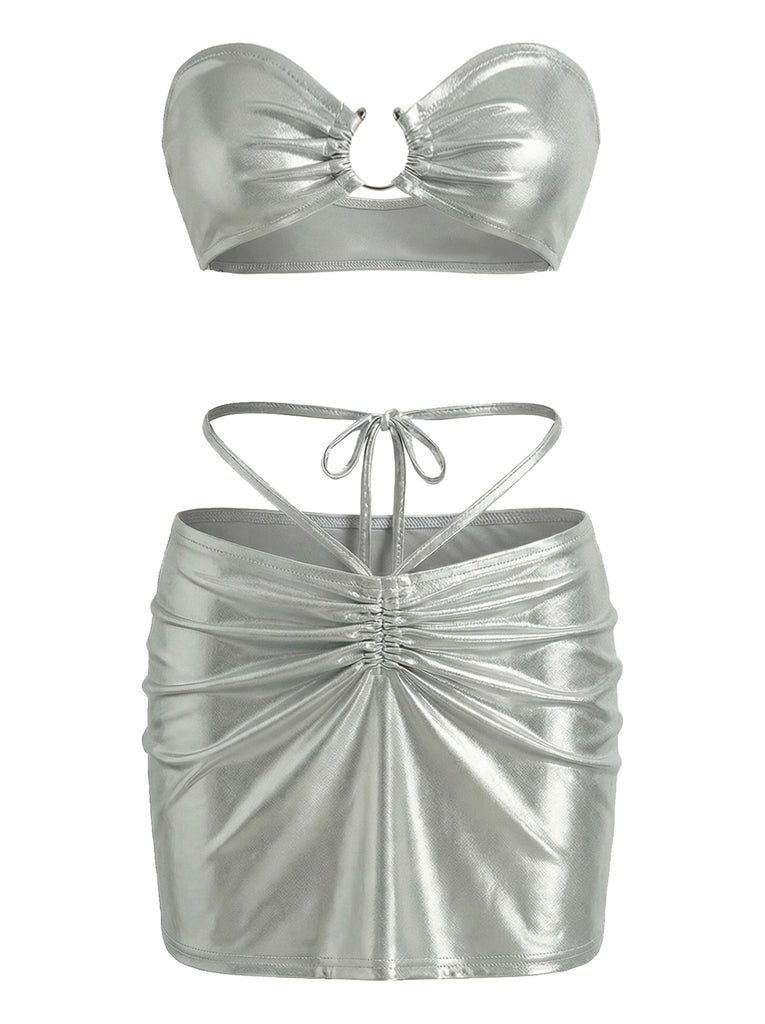 A metallic silver two-piece set featuring a strapless ruched bandeau top with a center ring detail and a matching high-waisted mini skirt with front ruching and tie-straps.
