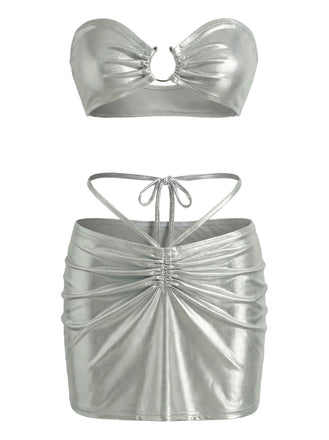 A metallic silver two-piece set featuring a strapless ruched bandeau top with a center ring detail and a matching high-waisted mini skirt with front ruching and tie-straps.