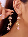 Close-up of a person wearing pink seashell and starfish earrings.
