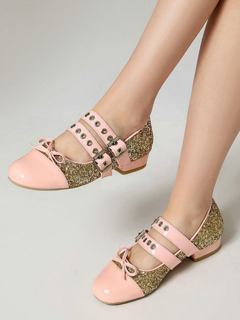 Pink and gold shoes with decorative straps on a neutral background