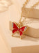 Red butterfly pendant necklace with gold chain on beige background