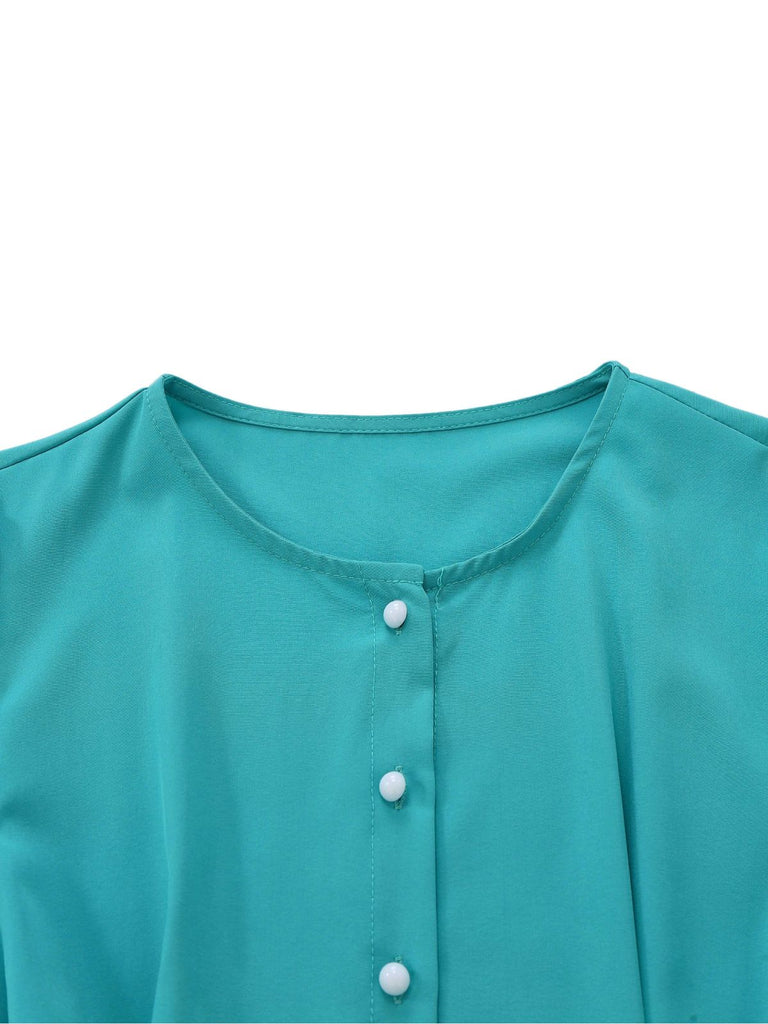 Close-up of the simple round neckline and the top white pearl buttons on the teal fabric.