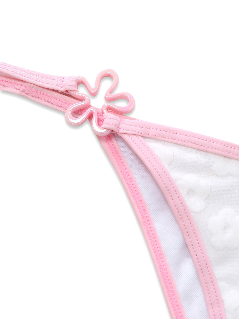 Detail of the pink side-tie strap on the bikini bottom featuring a small decorative flower charm.