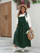 Full-length front view of the dark green pinafore maxi dress showing the side pockets and flowy silhouette.