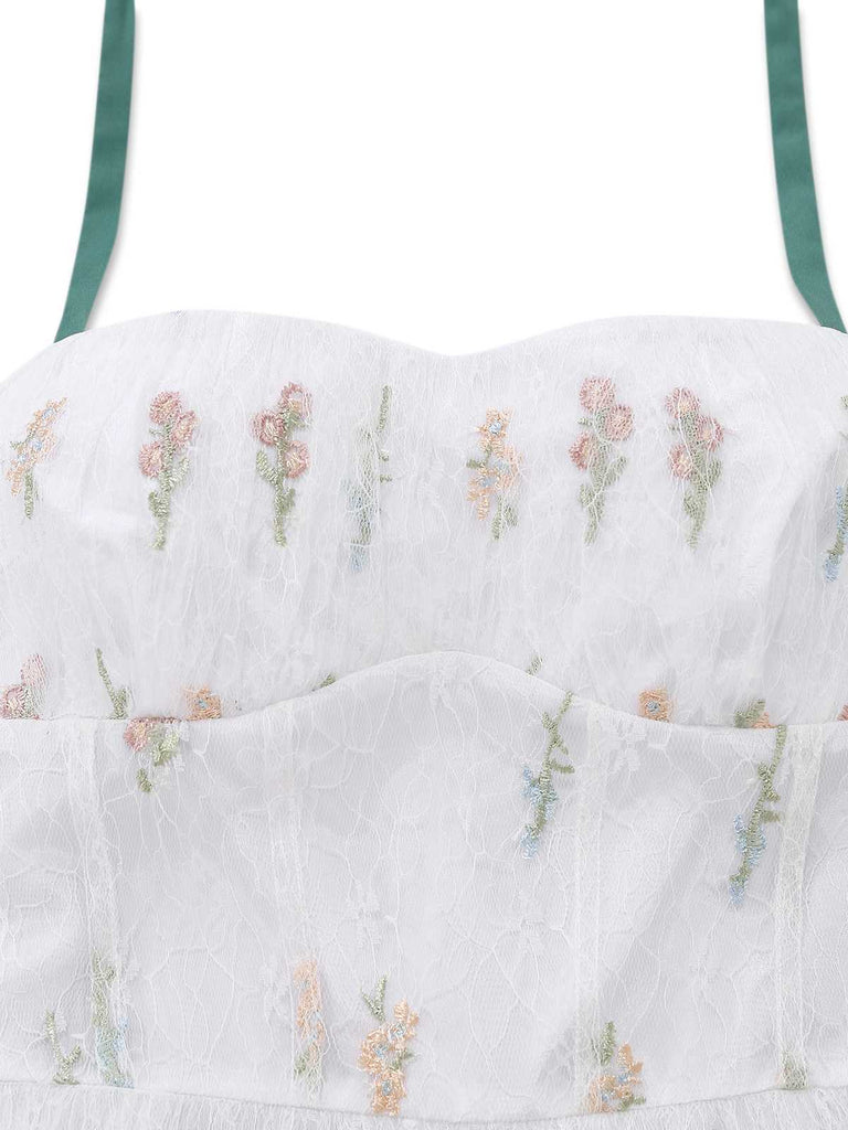 Close-up of the bodice featuring tiny colorful floral embroidery on the white mesh overlay.