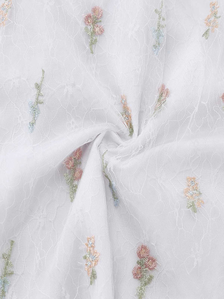 Macro view of the swirled tulle fabric highlighting the intricate and colorful wildflower embroidery.