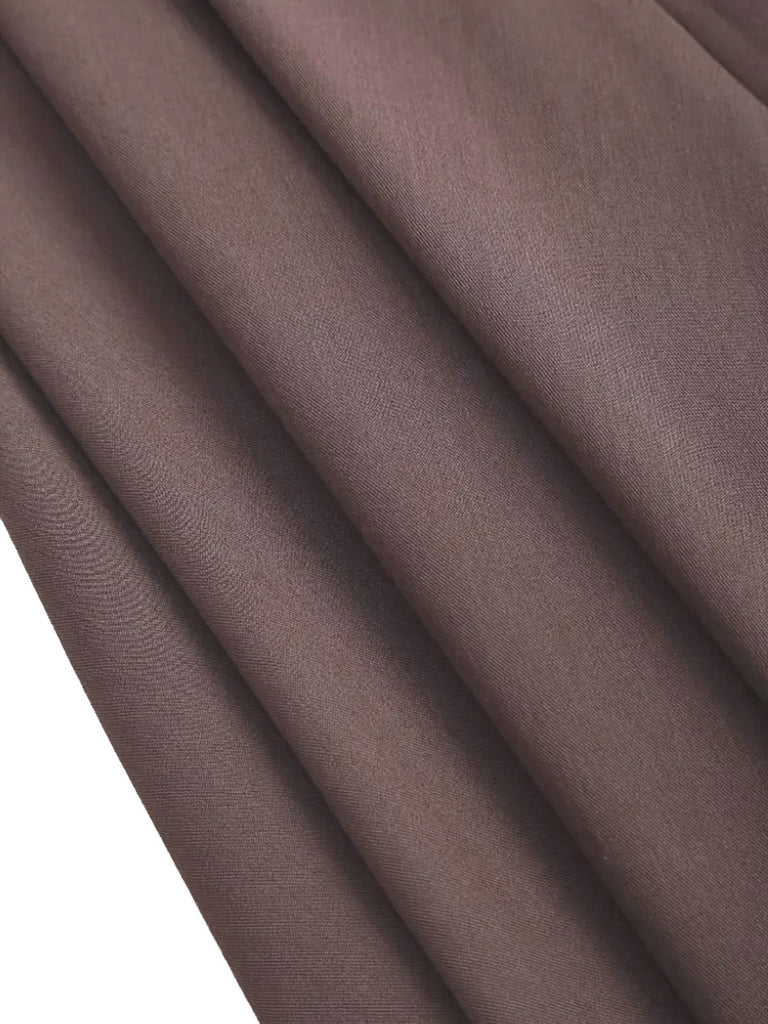 Detailed view of the taupe skirt's mid-weight textured fabric and the deep vertical pleat design.