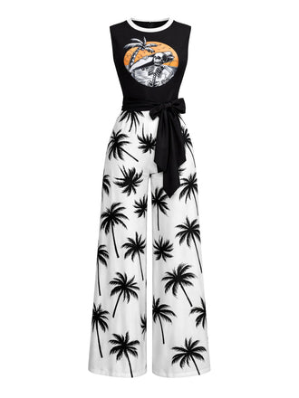 A black and white sleeveless jumpsuit featuring a palm tree print on the wide-leg pants and a graphic beach illustration on the black bodice with a tie-waist.