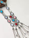 Close-up side view of the silver tribal-style necklace showing the intricate metalwork and oval colorful stone inlays.
