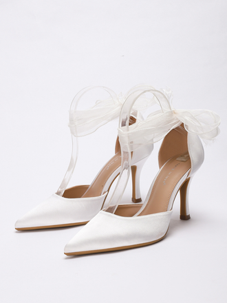 White high-heeled shoes with clear straps and bow on a white background