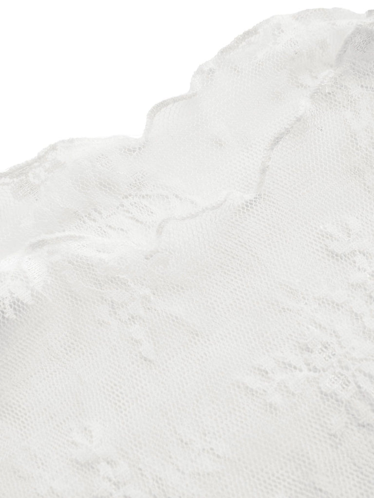 Detailed view of the white floral lace long-sleeve top paired with a black jumpsuit.