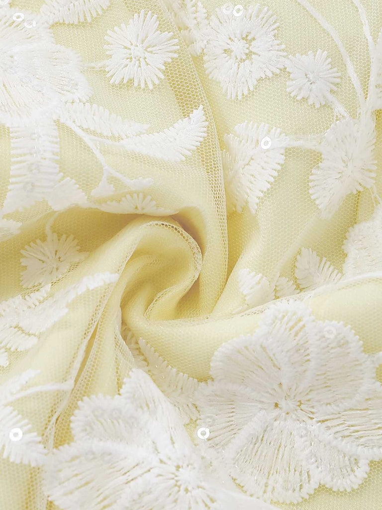 A macro view of the dress fabric showing the detailed texture of the yellow base and white lace overlay.